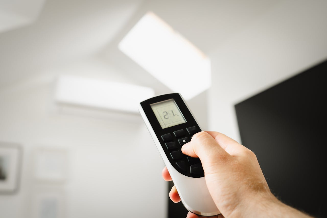 gallery-1 Close-up of a man using a remote to control air conditioning indoors.