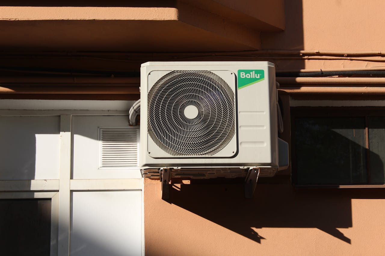 hero-img-02 A Ballu air conditioner condenser unit mounted on a building exterior, showcasing modern HVAC technology.