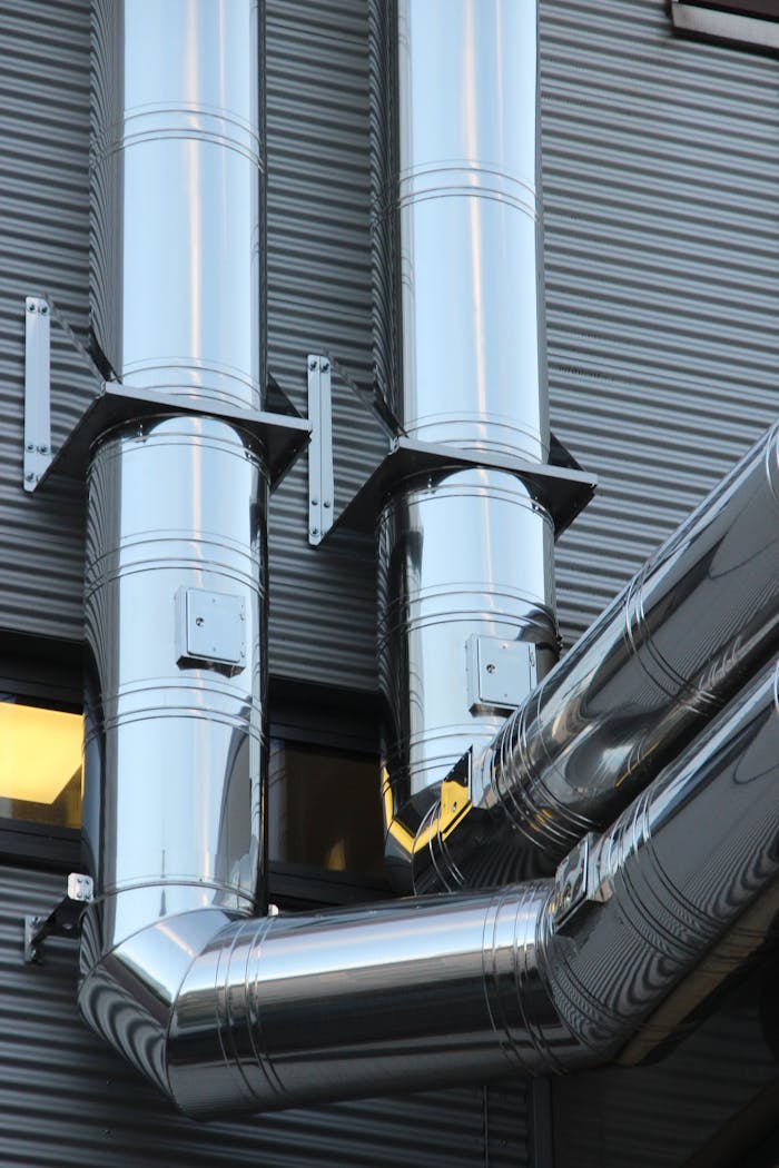 gallery-5 Close-up of shiny stainless steel pipes on an industrial building facade, showcasing modern technology.