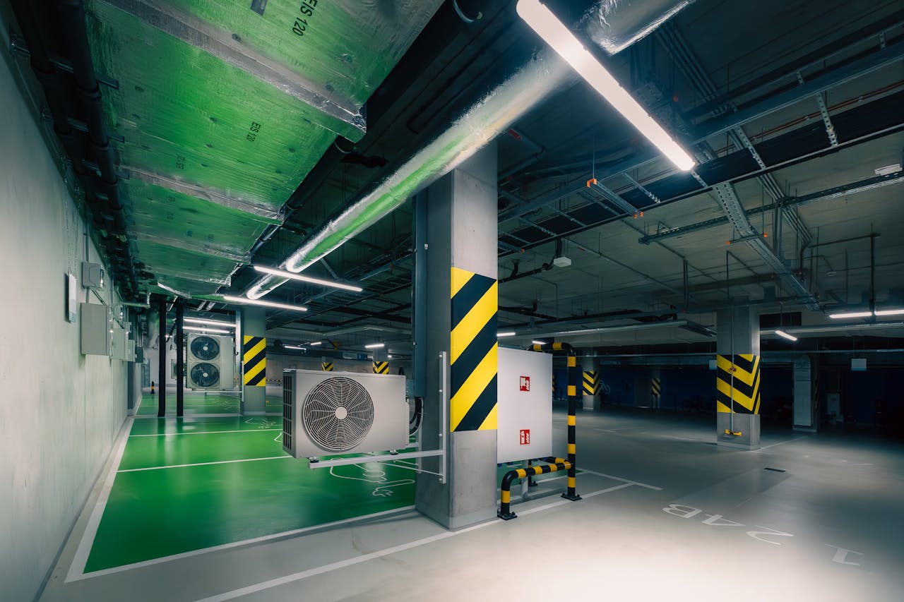 services-03 Sleek underground parking area with air conditioning units and green lighting.