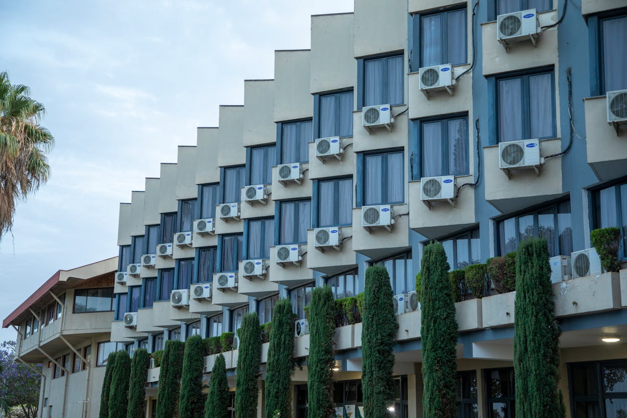gallery-4 Exterior view of a hotel building featuring rows of windows and air conditioning units, against a clear sky.