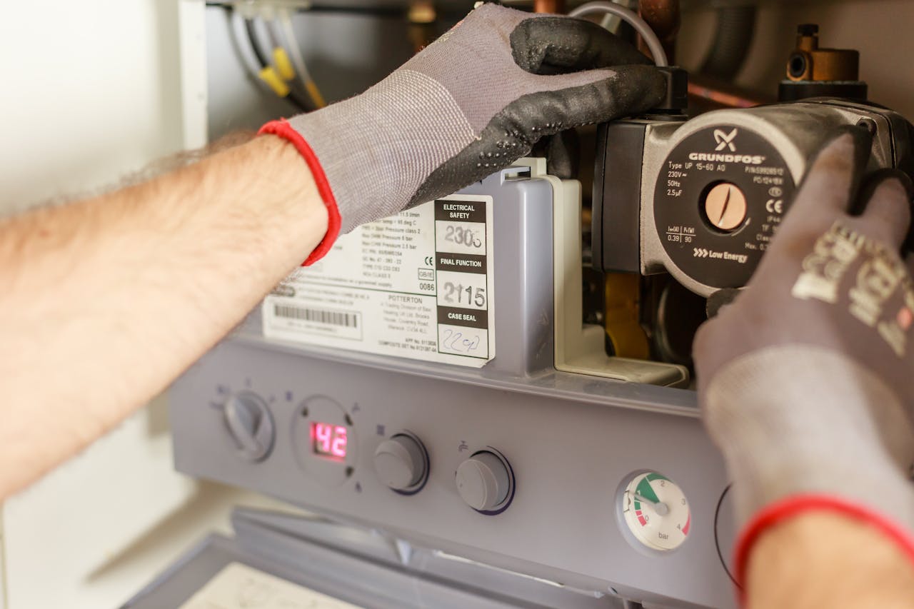 services-01 Close-up of hands adjusting a boiler system with precise instrumentation, showing maintenance work.